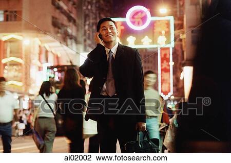 Stock Image - Hong Kong, male executive using cellular phone, carrying briefcase. Fotosearch