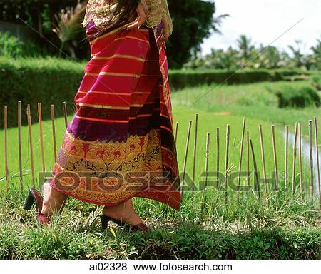 Stock Photo - Indonesia, Bali, Balinese dancer walking through fields, lower torso. Fotosearch