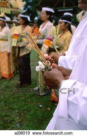 Indonesia, Bali, Gianyar, Pengastian ceremony, priest holding joss sticks, bell and flower, worshippers at background. (grainy) View Large Photo Image Stock Photo - Indonesia, Bali, Gianyar, Pengastian ceremony, priest holding joss sticks, bell and flower, worshippers at background. (grainy). Fotosearch