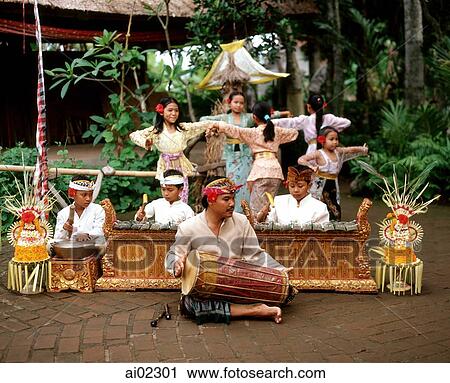 Indonesia, Bali, man playing hand drum, boys playing instruments and girls dancing in background in traditional costume View Large Photo Image Stock Image - Indonesia, Bali, man playing hand drum, boys playing instruments and girls dancing in background in traditional costume. Fotosearch