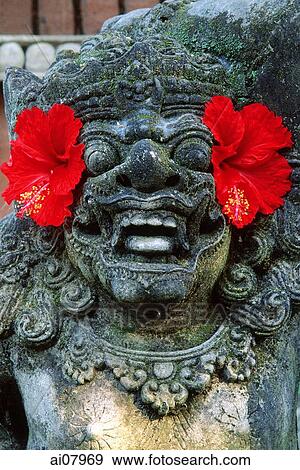 Indonesia, Bali, Sanur, Temple guardian adorned with Hibiscus flowers. (grainy) View Large Photo Image Stock Photo - Indonesia, Bali, Sanur, Temple guardian adorned with Hibiscus flowers. (grainy). Fotosearch