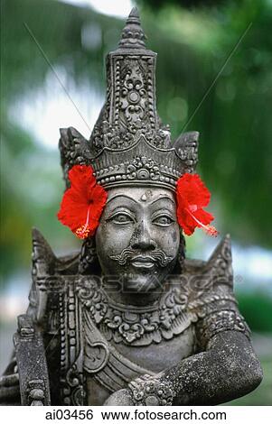 Stock Photograph - Indonesia, Bali, stone statue with flowers. Fotosearch