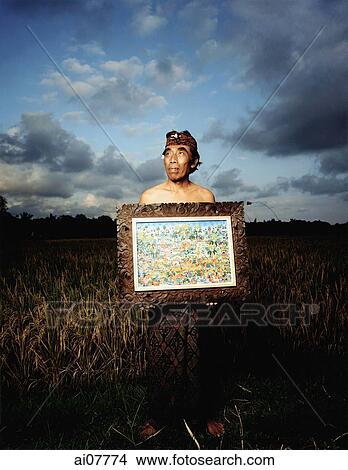 Indonesia, Bali, Ubud, Balinese artist holding painting in rice field. View Large Photo Image Picture - Indonesia, Bali, Ubud, Balinese artist holding painting in rice field.. Fotosearch