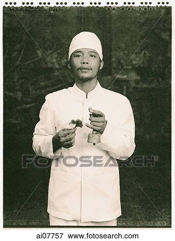 Indonesia, Bali, Ubud, Balinese Hindu priest holding ceremonial bell and flowers in temple courtyard. View Large Photo Image Stock Photo - Indonesia, Bali, Ubud, Balinese Hindu priest holding ceremonial bell and flowers in temple courtyard.. Fotosearch