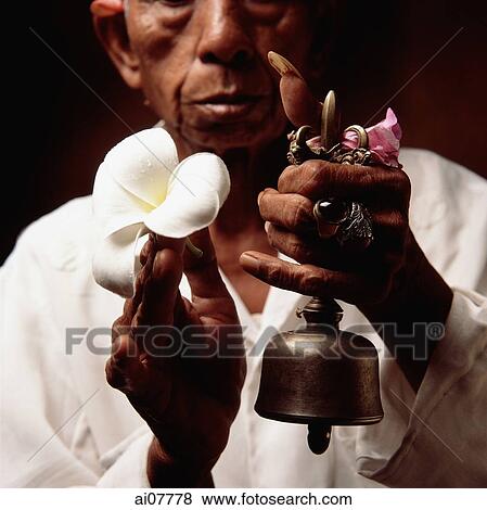 Indonesia, Bali, Ubud, Hindu priest holding prayer bell and Frangipani flower. View Large Photo Image Stock Photo - Indonesia, Bali, Ubud, Hindu priest holding prayer bell and Frangipani flower.. Fotosearch
