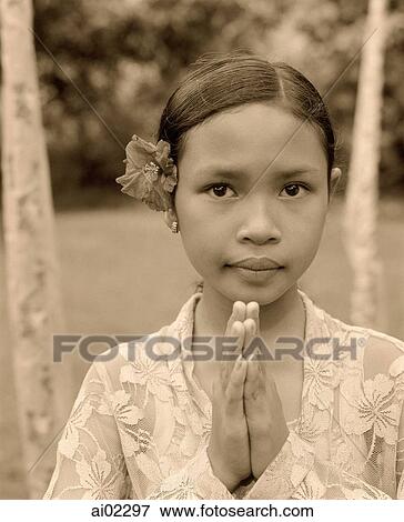 Indonesia, Bali, young girl with flower behind ear, traditional greeting, portrait View Large Photo Image Stock Photo - Indonesia, Bali, young girl with flower behind ear, traditional greeting, portrait. Fotosearch