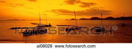 Indonesia, Flores, Labuanbajo, Sunset across beach, fishing boats in foreground. (grainy) View Large Photo Image Stock Photo - Indonesia, Flores, Labuanbajo, Sunset across beach, fishing boats in foreground. (grainy). Fotosearch