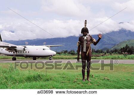 Stock Photo - Indonesia, Irian Jaya, Dani warrior, modern plane in background. Fotosearch