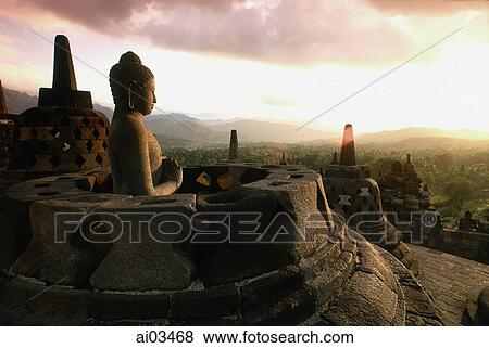 Indonesia, Java, Buddha figure at Borobudur temple at dawn, mountains in background View Large Photo Image Stock Photo - Indonesia, Java, Buddha figure at Borobudur temple at dawn, mountains in background. Fotosearch