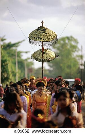Stock Image - Indonesia, Lombok, a bride walking under a canopy and accompanied by female attendants, following musicians to the groom's home.. Fotosearch