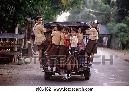 Stock Image - Indonesia, Lombok, Schoolboys riding on the back of a van.. Fotosearch