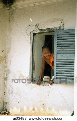 Laos, Luang Prabang, Young monk looking out of window at monastery View Large Photo Image Stock Photo - Laos, Luang Prabang, Young monk looking out of window at monastery. Fotosearch