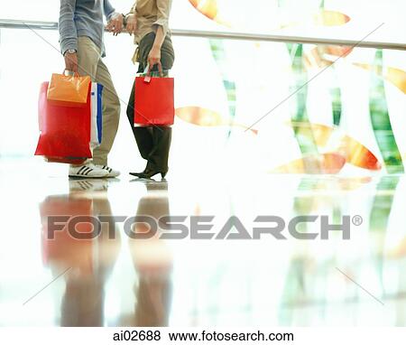 Lower body of couple holding shopping bags, talking and leaning on railing. View Large Photo Image Stock Photo - Lower body of couple holding shopping bags, talking and leaning on railing.. Fotosearch