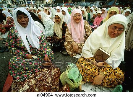 Picture - Malaysia, Kota Bharu, overflow crowd of women listen to a sermon on a dusty street outside a local mosque.. Fotosearch