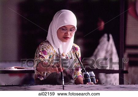 Malaysia, Kuala Terengganu, Muslim woman wearing tudung paints fabric at batik factory. View Large Photo Image Stock Photo - Malaysia, Kuala Terengganu, Muslim woman wearing tudung paints fabric at batik factory.. Fotosearch