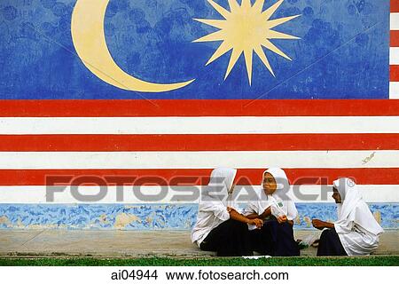 Malaysia, Kukup, three Muslim schoolgirls chatting in front of a large Malaysian flag painted on the wall behind them. View Large Photo Image Picture - Malaysia, Kukup, three Muslim schoolgirls chatting in front of a large Malaysian flag painted on the wall behind them.. Fotosearch