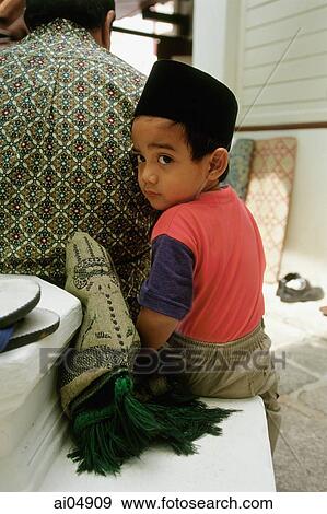 Malaysia, Malacca, Muslim boy with prayer rug nestles besides his father before Friday prayers at Kampong Kling Mosque. View Large Photo Image Stock Photo - Malaysia, Malacca, Muslim boy with prayer rug nestles besides his father before Friday prayers at Kampong Kling Mosque.. Fotosearch