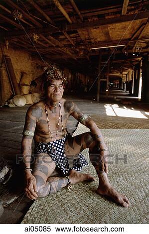 Malaysia, Sarawak, Iban man in traditional dress sitting inside long house View Large Photo Image Stock Photography - Malaysia, Sarawak, Iban man in traditional dress sitting inside long house. Fotosearch