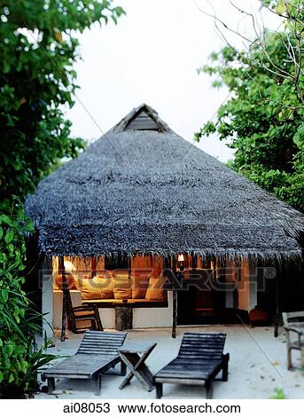 Stock Image - Maldives, Kunfunadhoo atoll, Soneva Fushi, Thatched villa in early evening.. Fotosearch