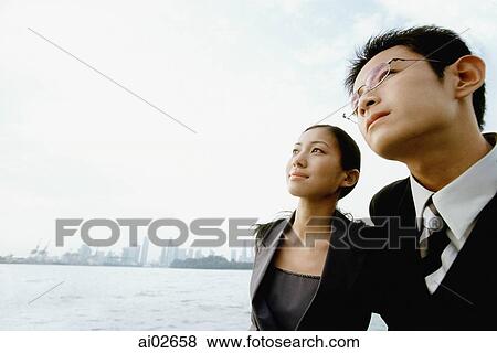 Male and female executive looking up, blue sky in background, portrait View Large Photo Image Stock Photo - Male and female executive looking up, blue sky in background, portrait. Fotosearch