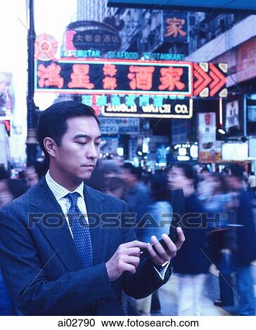 Male executive dialing cellular phone in busy street, neon lights in background. View Large Photo Image Stock Image - Male executive dialing cellular phone in busy street, neon lights in background.. Fotosearch