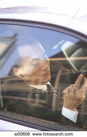 Male executive holding cellular phone hands-free set in car View Large Photo Image Stock Photo - Male executive holding cellular phone hands-free set in car. Fotosearch