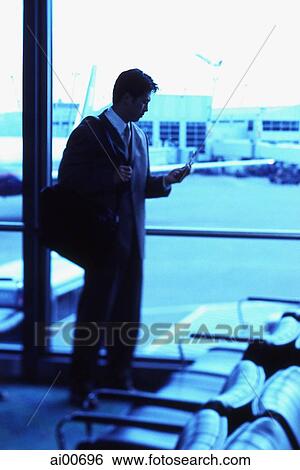 Male executive holding cellular phone in airport lounge View Large Photo Image Stock Photograph - Male executive holding cellular phone in airport lounge. Fotosearch