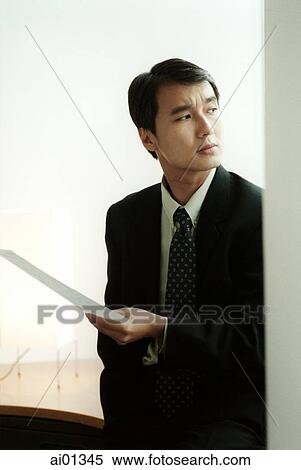 Male executive holding document, looking away View Large Photo Image Stock Photography - Male executive holding document, looking away. Fotosearch