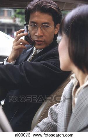 Stock Image - Male executive in car talking on cellular phone. Fotosearch