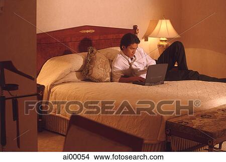 Picture - Male executive in hotel room working on laptop computer. Fotosearch