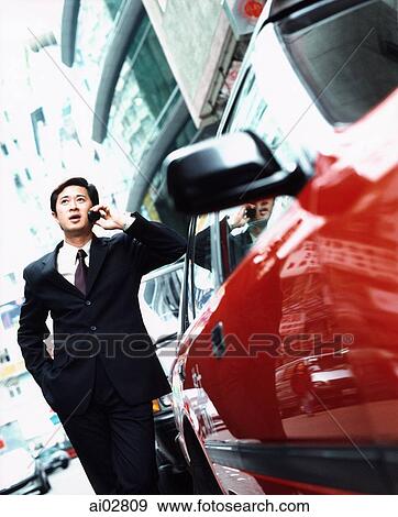 Male executive leaning on car using cellular phone. View Large Photo Image Stock Photo - Male executive leaning on car using cellular phone.. Fotosearch