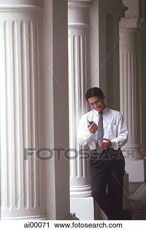 Male executive looking at cellular phone, pillars behind View Large Photo Image Stock Image - Male executive looking at cellular phone, pillars behind. Fotosearch