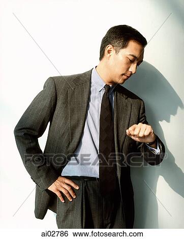 Male executive looking at watch against white background. View Large Photo Image Stock Photograph - Male executive looking at watch against white background.. Fotosearch