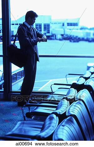 Male executive looking at watch in airport lounge View Large Photo Image Picture - Male executive looking at watch in airport lounge. Fotosearch