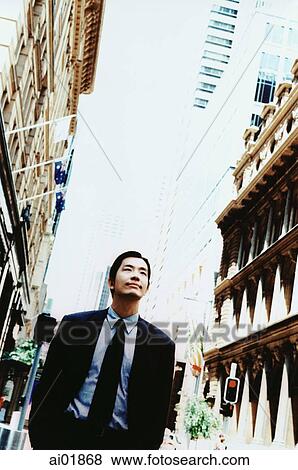 Stock Photo - Male executive looking upwards, buildings on either side ( high grain). Fotosearch