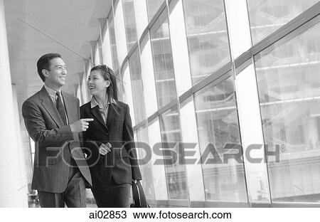 Male executive pointing out something to female while walking down hall. View Large Photo Image Stock Image - Male executive pointing out something to female while walking down hall.. Fotosearch