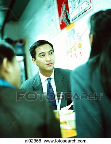 Male executive seated with colleagues at restaurant eating. View Large Photo Image Stock Photo - Male executive seated with colleagues at restaurant eating.. Fotosearch