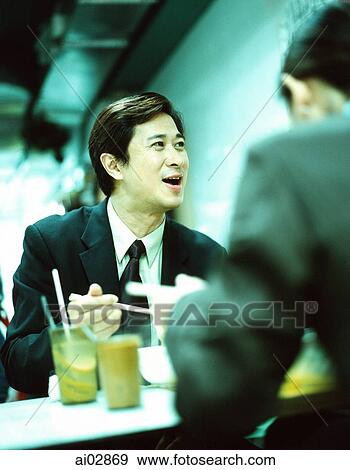 Male executive seated with colleagues at restaurant eating. View Large Photo Image Stock Photo - Male executive seated with colleagues at restaurant eating.. Fotosearch