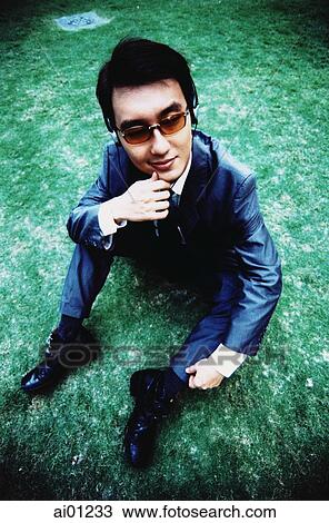 Male executive sitting on grass ( high grain) View Large Photo Image Stock Image - Male executive sitting on grass ( high grain). Fotosearch