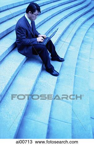 Male executive sitting on steps using laptop View Large Photo Image Stock Image - Male executive sitting on steps using laptop. Fotosearch