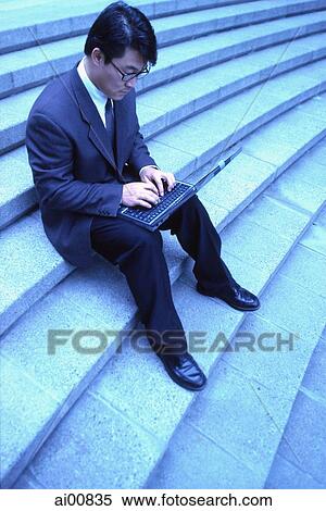 Male executive sitting on steps, using laptop View Large Photo Image Stock Photography - Male executive sitting on steps, using laptop. Fotosearch