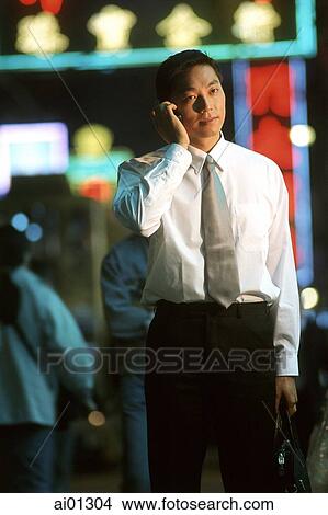 Male executive talking on cellular phone, neon in background View Large Photo Image Picture - Male executive talking on cellular phone, neon in background. Fotosearch