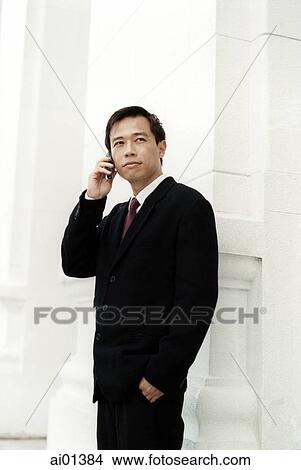 Picture - Male executive talking on cellular phone, white building in background.. Fotosearch