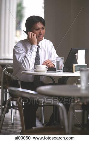 Stock Image - Male executive talking on cellular phone in cafe. Fotosearch