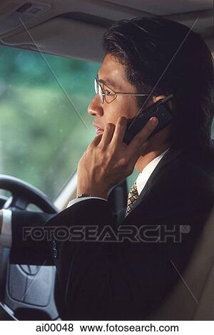 Stock Photo - Male executive talking on cellular phone in car, profile. Fotosearch
