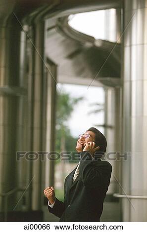 Male executive talking on cellular phone, office building behind View Large Photo Image Stock Photograph - Male executive talking on cellular phone, office building behind. Fotosearch