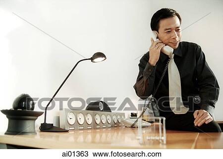 Stock Image - Male executive talking on phone at desk.. Fotosearch