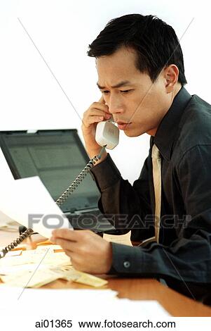 Stock Photography - Male executive talking on phone with laptop behind.. Fotosearch