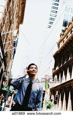 Male executive using cellular phone, buildings on either side ( high grain) View Large Photo Image Stock Photo - Male executive using cellular phone, buildings on either side ( high grain). Fotosearch