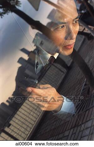 Male executive with cellular phone, skyline reflected in car window View Large Photo Image Picture - Male executive with cellular phone, skyline reflected in car window. Fotosearch